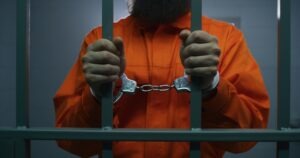 man in handcuffs behind bars