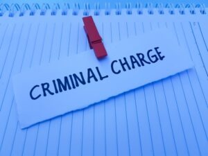criminal charge on paper clipped to another paper