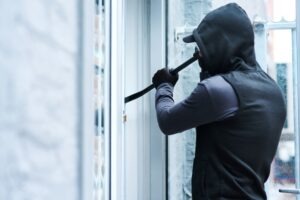 man using crowbar to break into a house