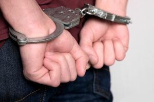 a man in handcuffs wondering what is first degree burglary in arizona