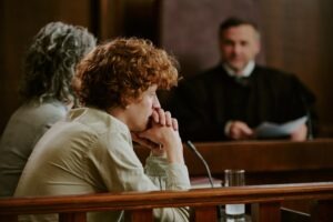 Teenager sitting in a courtroom next to their lawyer, with the attorney discussing the Romeo and Juliet law in Arizona with a judge nearby