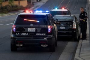 Two police cars parked in front of and behind a passenger vehicle during a traffic stop, leaving the civilian driver to wonder what steps to follow to protect their rights when the police stop their car.